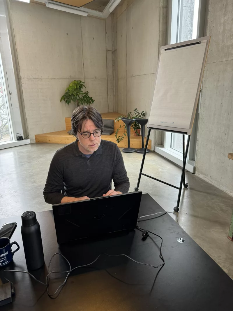 Oliver Werner arbeitet konzentriert am Laptop neben einem Flipchart