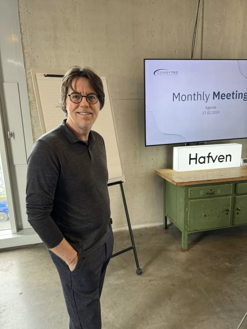 Oliver Werner im Coworking-Space Hafven Hannover vor einem Präsentationsbildschirm